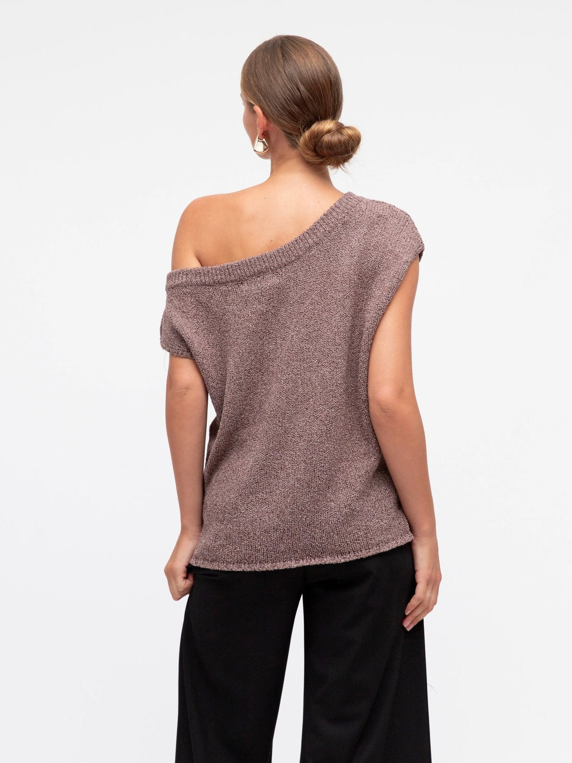 Model wearing a one-shoulder brown knit top on a white background at Wanted and Wild