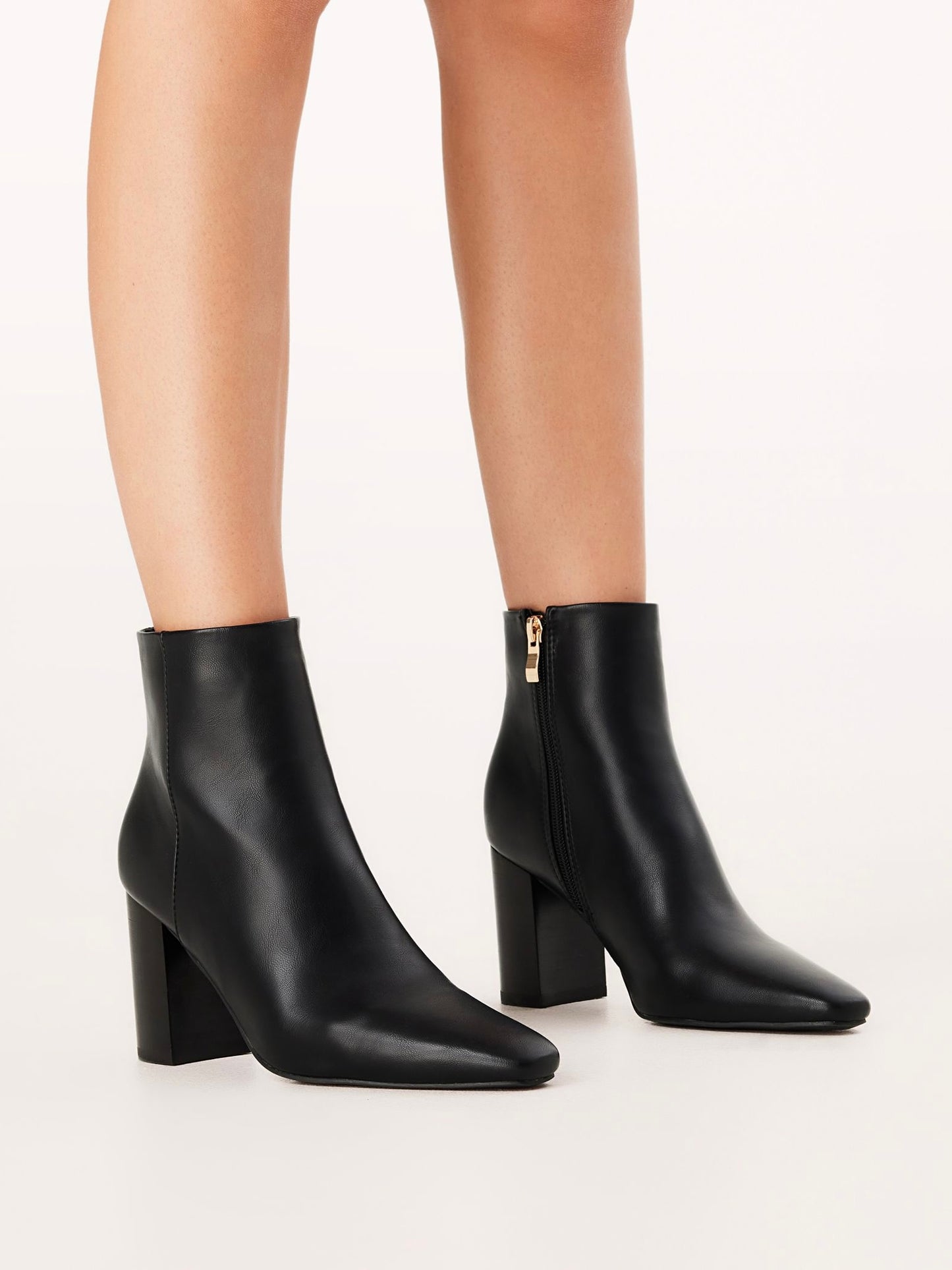 Black ankle boots worn by a person on a white background