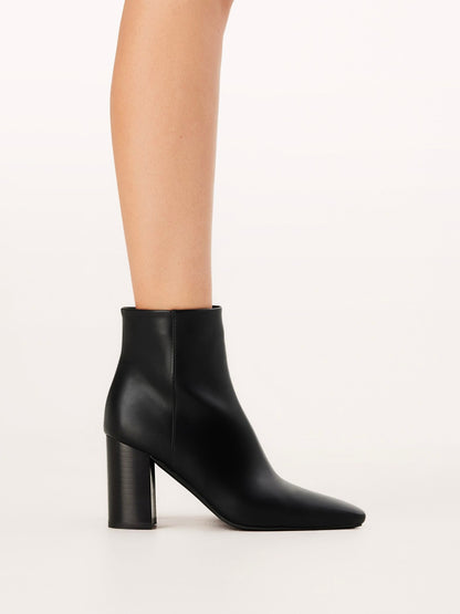 Black ankle boot worn by a person on a white background