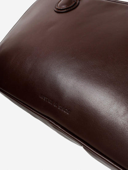 Close-up of a brown leather bag with 'Lustre and Sage' branding on a white background