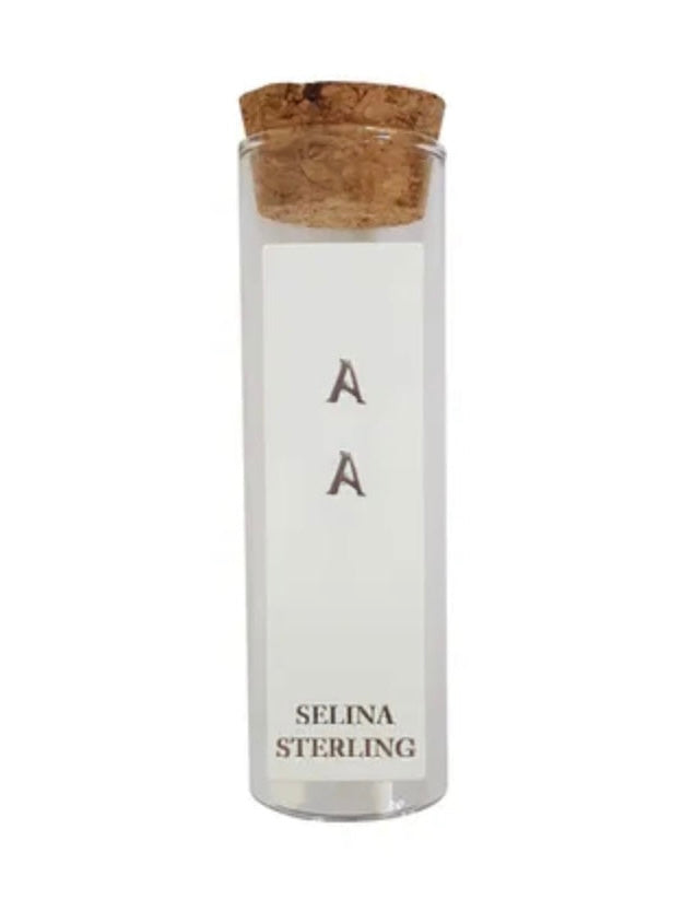 A pair of silver stud earrings with the letter 'A' on them, packaged in a small glass container with a cork lid, available at Wanted and Wild.