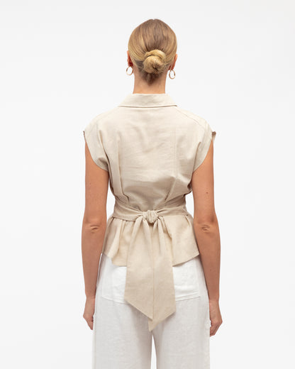 Woman wearing a beige sleeveless shirt with a tie waist on a white background. Back view