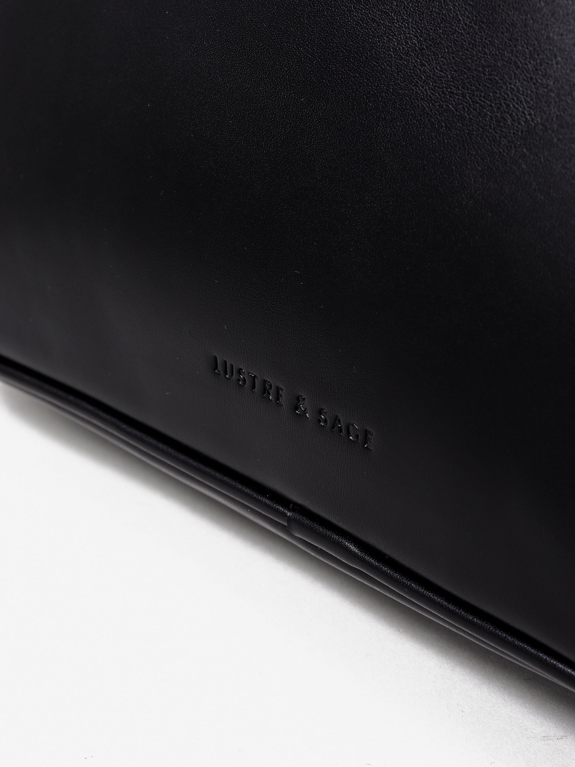 Black leather wallet with 'Lustre and Sage ' branding on a white background