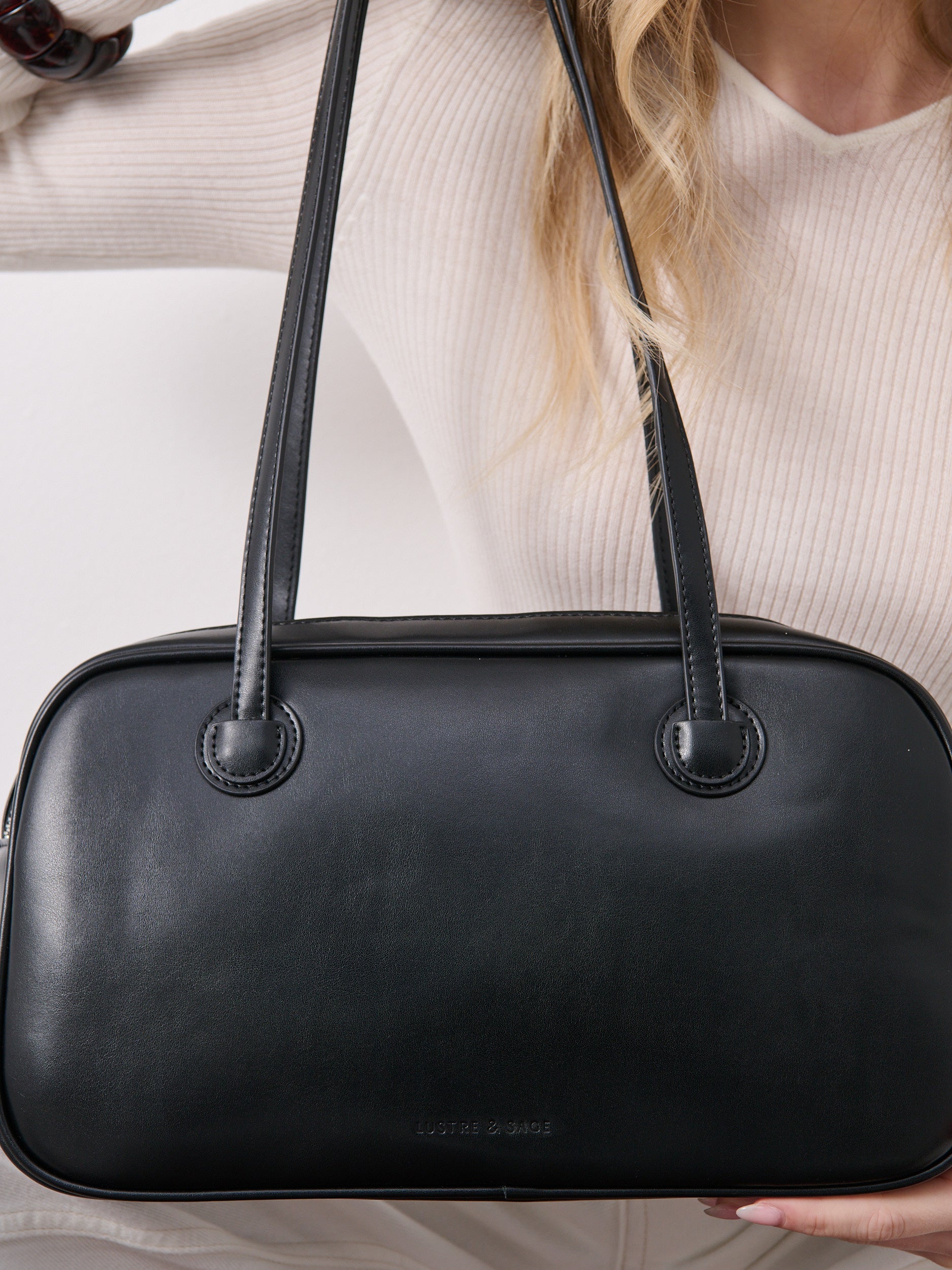 Brenna Black handbag held by a person wearing a white sweater at Wanted and Wild
